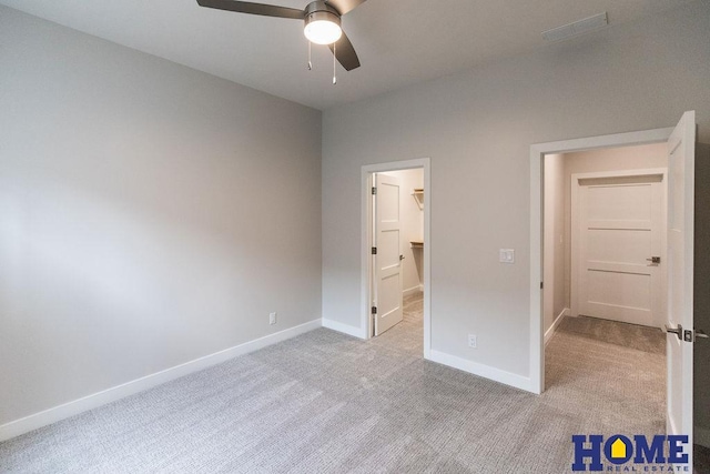 unfurnished bedroom with ceiling fan, light colored carpet, and a walk in closet