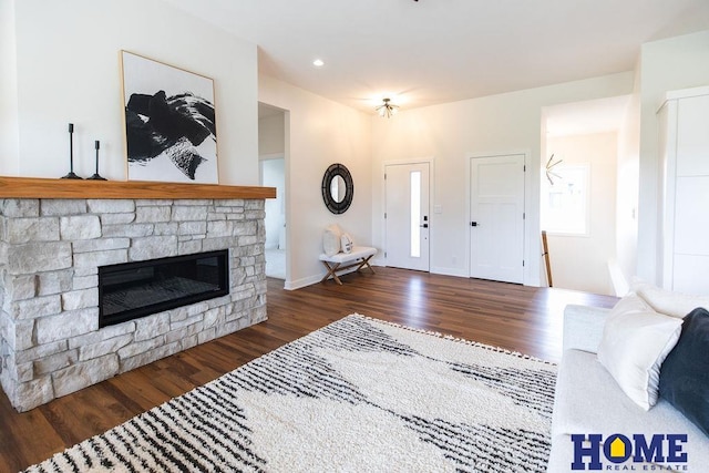 living room with dark hardwood / wood-style floors and a stone fireplace