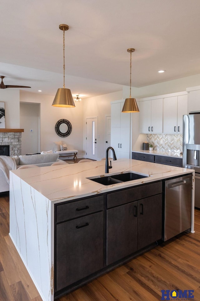 kitchen featuring white cabinetry, an island with sink, stainless steel appliances, hanging light fixtures, and sink