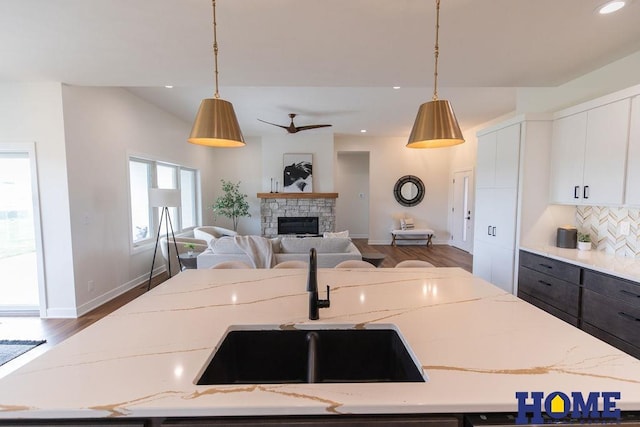 kitchen featuring white cabinetry, backsplash, light stone counters, and hanging light fixtures