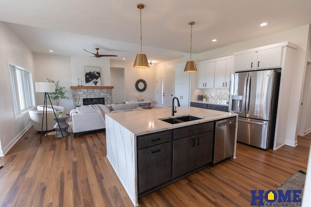 kitchen featuring appliances with stainless steel finishes, decorative light fixtures, white cabinetry, sink, and backsplash