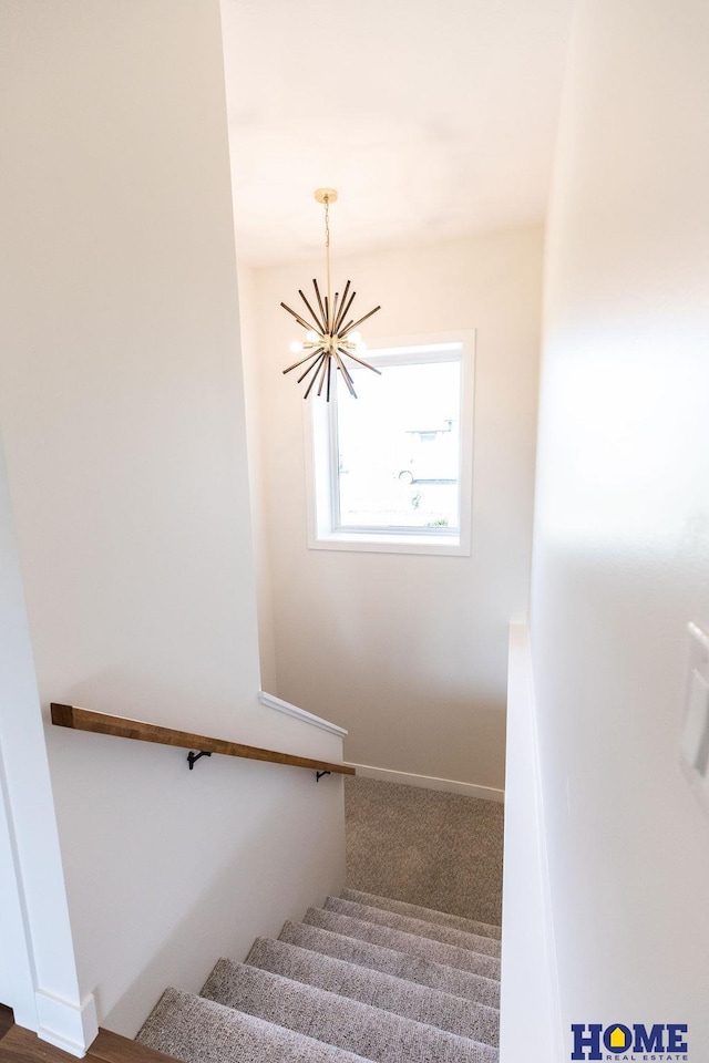 staircase featuring an inviting chandelier and carpet