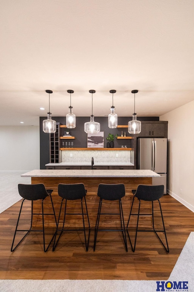 bar with dark hardwood / wood-style flooring, pendant lighting, and stainless steel fridge