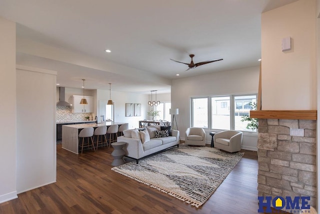 living room with dark hardwood / wood-style floors and ceiling fan with notable chandelier