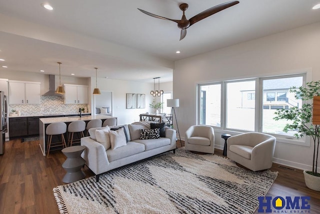 living room with dark wood-type flooring, ceiling fan with notable chandelier, and sink