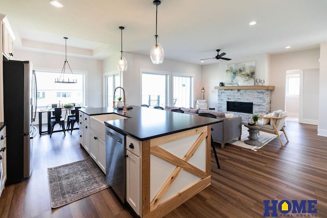 kitchen with white cabinetry, stainless steel appliances, a healthy amount of sunlight, sink, and a center island with sink