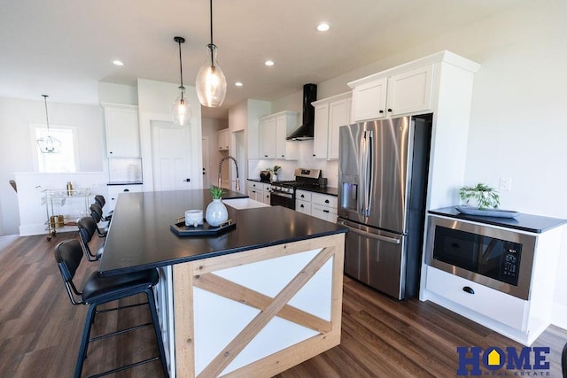 kitchen with decorative light fixtures, wall chimney range hood, dark wood-type flooring, stainless steel appliances, and white cabinets