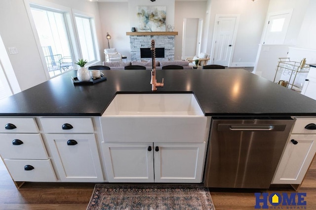 kitchen featuring stainless steel dishwasher, white cabinets, dark hardwood / wood-style flooring, and sink