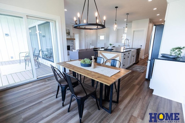 dining room with a healthy amount of sunlight, dark hardwood / wood-style flooring, sink, and a stone fireplace