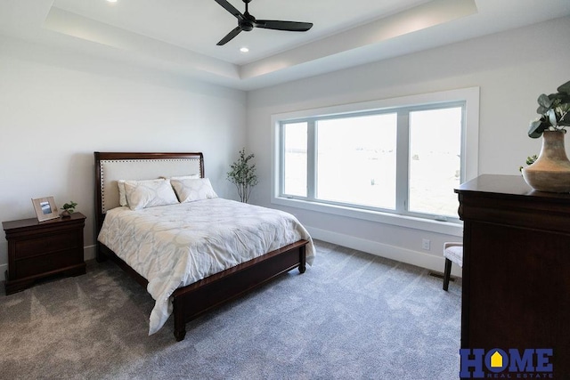 carpeted bedroom featuring a raised ceiling and ceiling fan