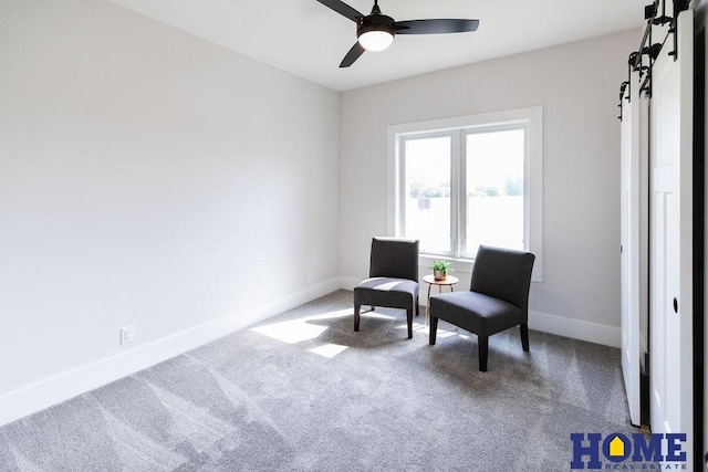 sitting room featuring ceiling fan, a barn door, and carpet floors