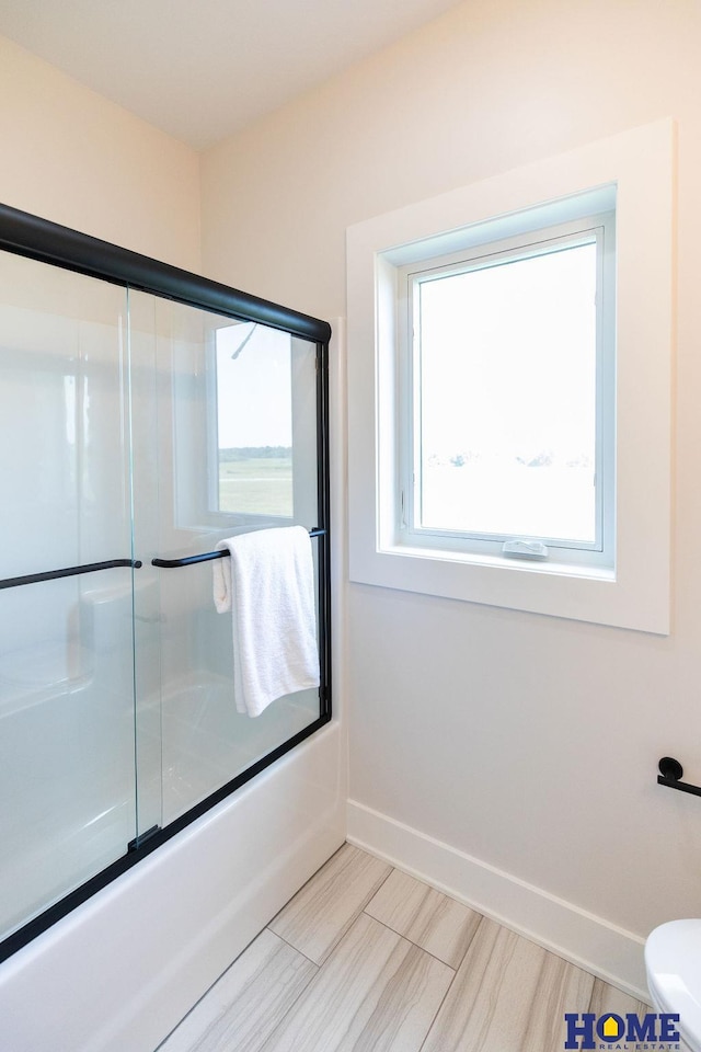 bathroom featuring bath / shower combo with glass door and toilet