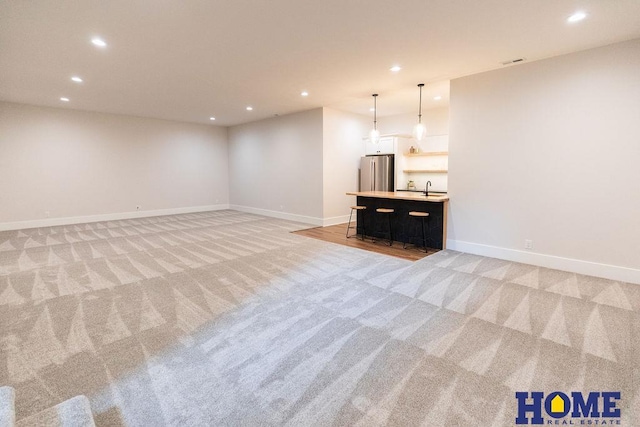 unfurnished living room featuring light carpet and sink