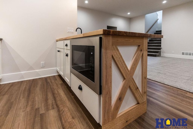 details featuring dark wood-type flooring, white cabinetry, and black microwave