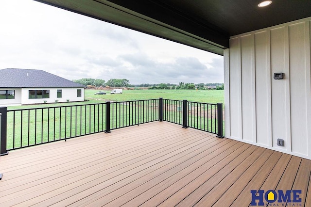 wooden terrace with a rural view and a yard