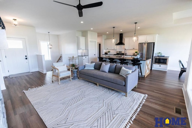 living room with ceiling fan, sink, and dark hardwood / wood-style floors