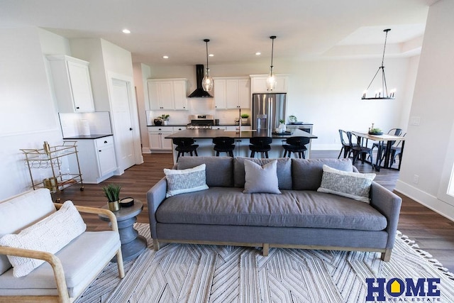 living room with dark hardwood / wood-style floors, a raised ceiling, and a notable chandelier