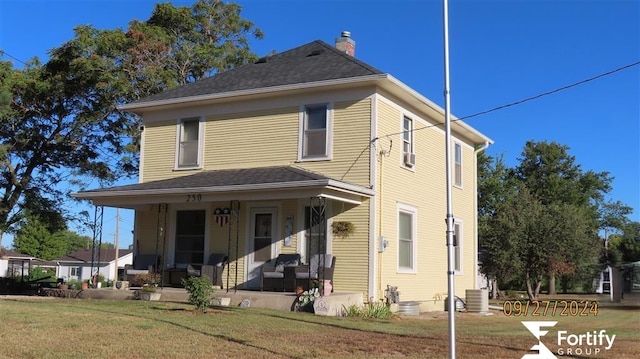 view of front of property with a porch, a front yard, a chimney, and central AC unit