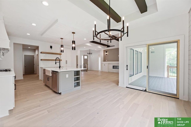 kitchen with white cabinets, dishwasher, hanging light fixtures, a kitchen island with sink, and a chandelier