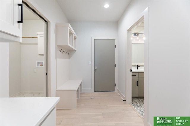 mudroom with sink and light hardwood / wood-style flooring