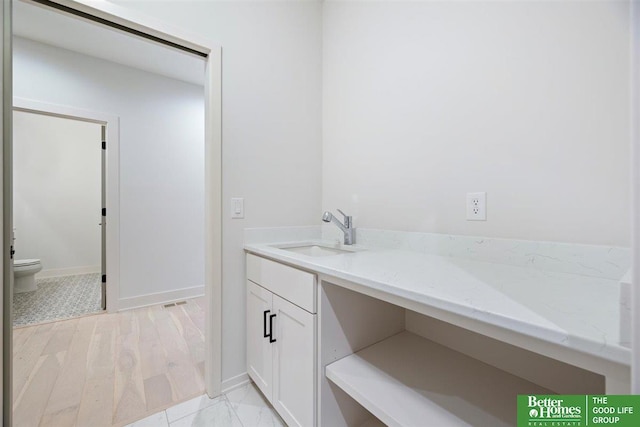 bathroom with toilet, hardwood / wood-style floors, and vanity