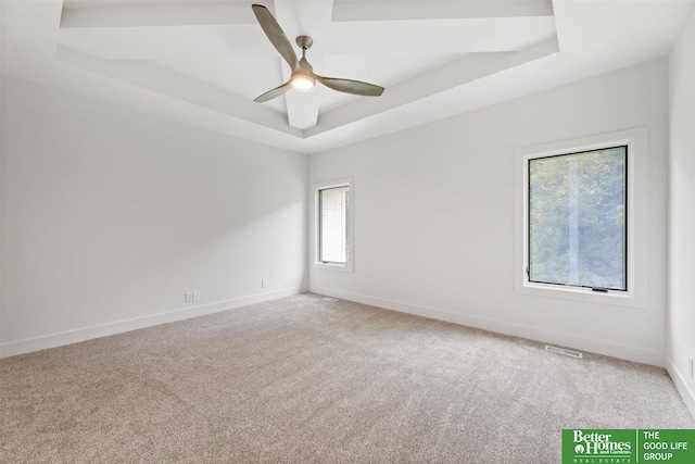 carpeted spare room with ceiling fan and a tray ceiling