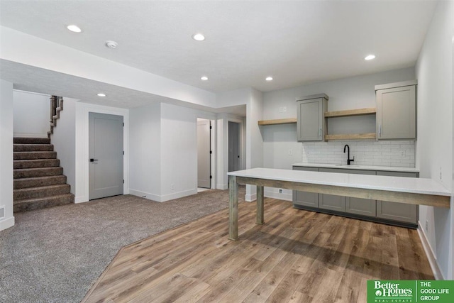 kitchen featuring sink, backsplash, gray cabinetry, and dark colored carpet