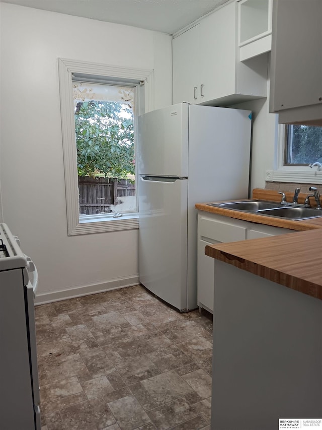 kitchen featuring white cabinets, sink, wood counters, and white appliances