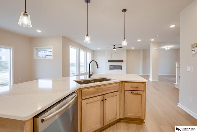 kitchen with pendant lighting, light brown cabinetry, sink, a kitchen island with sink, and stainless steel dishwasher