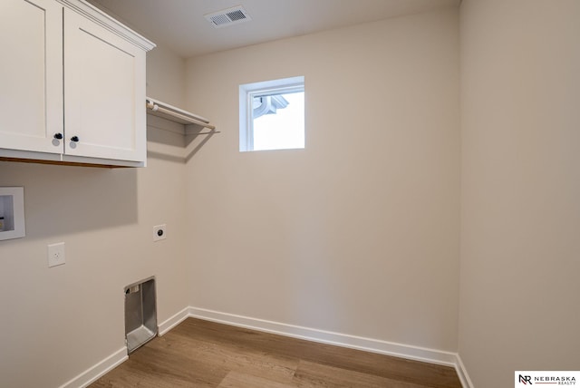 laundry room featuring light hardwood / wood-style floors, cabinets, hookup for a washing machine, and electric dryer hookup