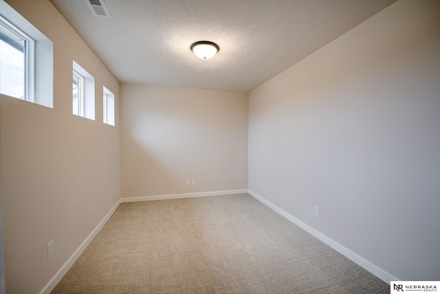 carpeted empty room with a textured ceiling