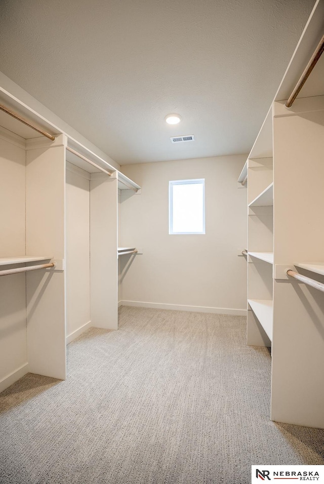 walk in closet featuring light carpet