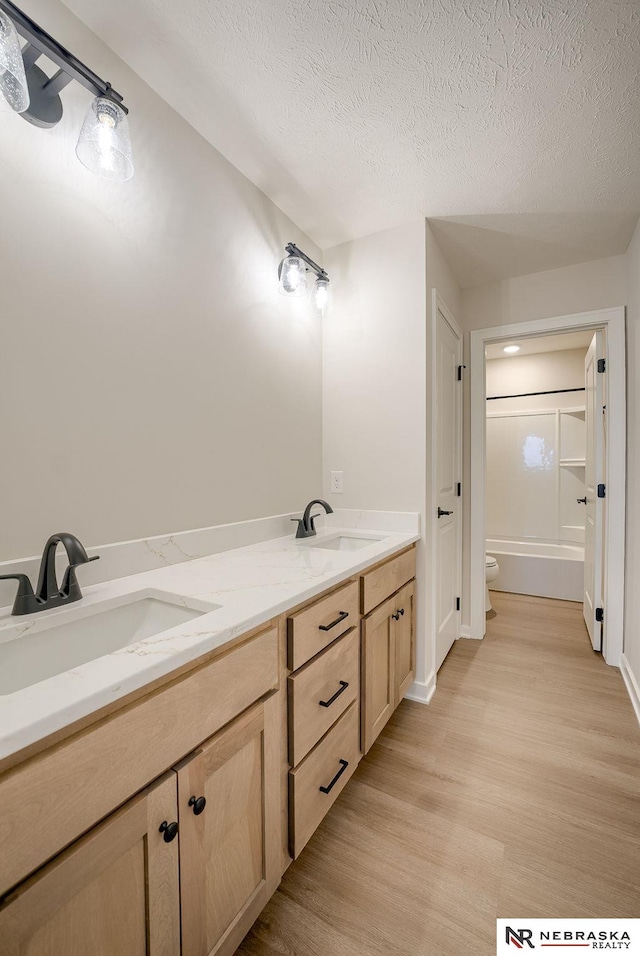 bathroom featuring a textured ceiling, toilet, hardwood / wood-style flooring, and vanity