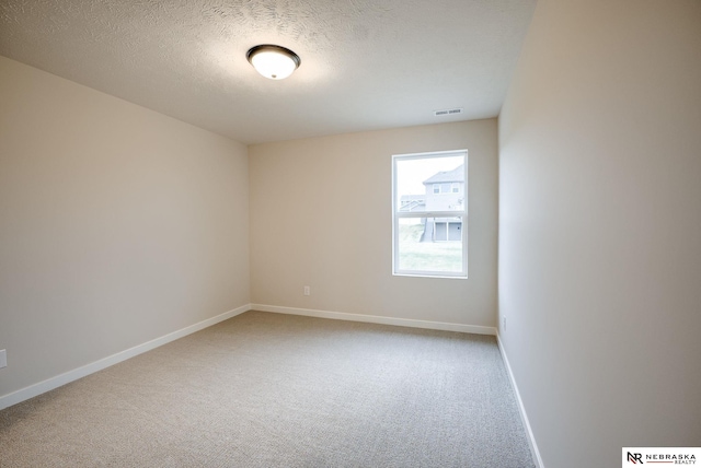 carpeted empty room featuring a textured ceiling