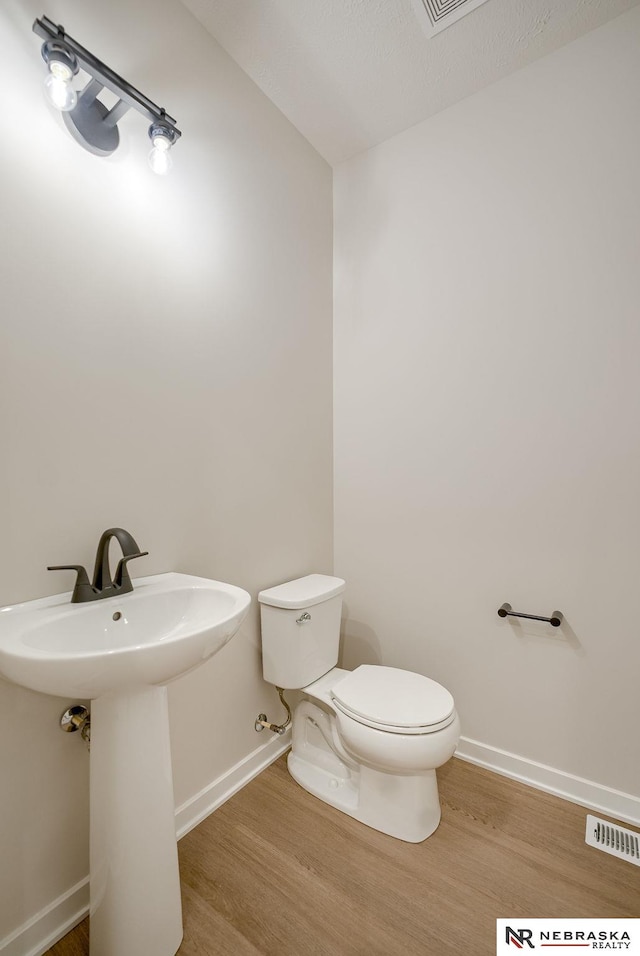 bathroom with toilet, sink, and hardwood / wood-style floors