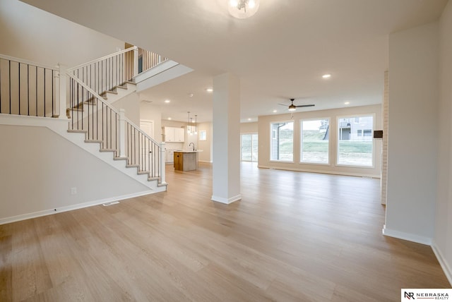 unfurnished living room with light wood-type flooring, ceiling fan, and sink