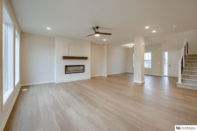 unfurnished living room featuring ceiling fan, light hardwood / wood-style floors, and a fireplace