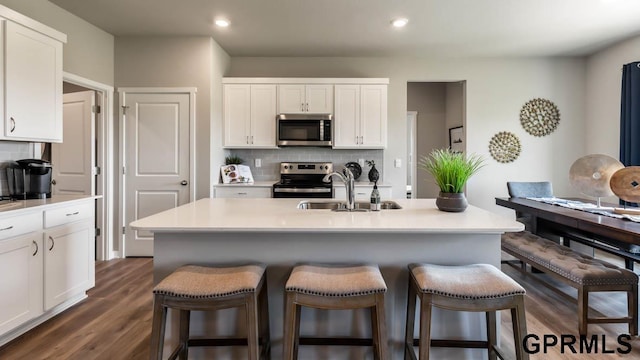 kitchen with appliances with stainless steel finishes, tasteful backsplash, and an island with sink