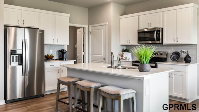 kitchen with tasteful backsplash, sink, a kitchen island with sink, appliances with stainless steel finishes, and white cabinets