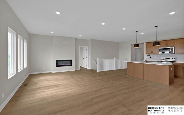 kitchen featuring pendant lighting, sink, light hardwood / wood-style flooring, an island with sink, and stainless steel appliances