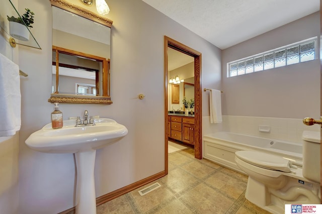 bathroom featuring sink, a textured ceiling, a tub to relax in, and toilet