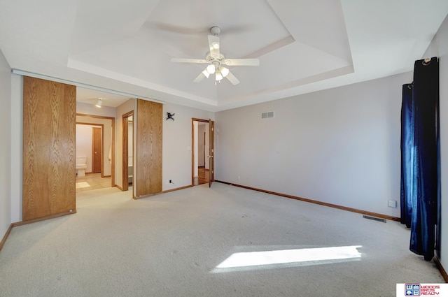 spare room with light carpet, ceiling fan, and a tray ceiling