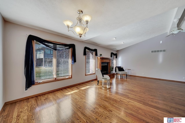 unfurnished room featuring a chandelier, hardwood / wood-style floors, and lofted ceiling