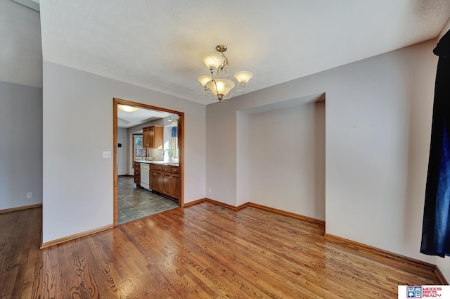 unfurnished room with a notable chandelier and light wood-type flooring