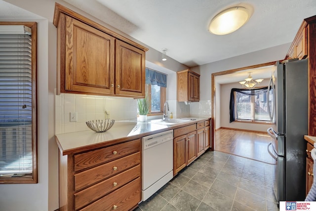 kitchen with sink, stainless steel refrigerator, white dishwasher, and a healthy amount of sunlight