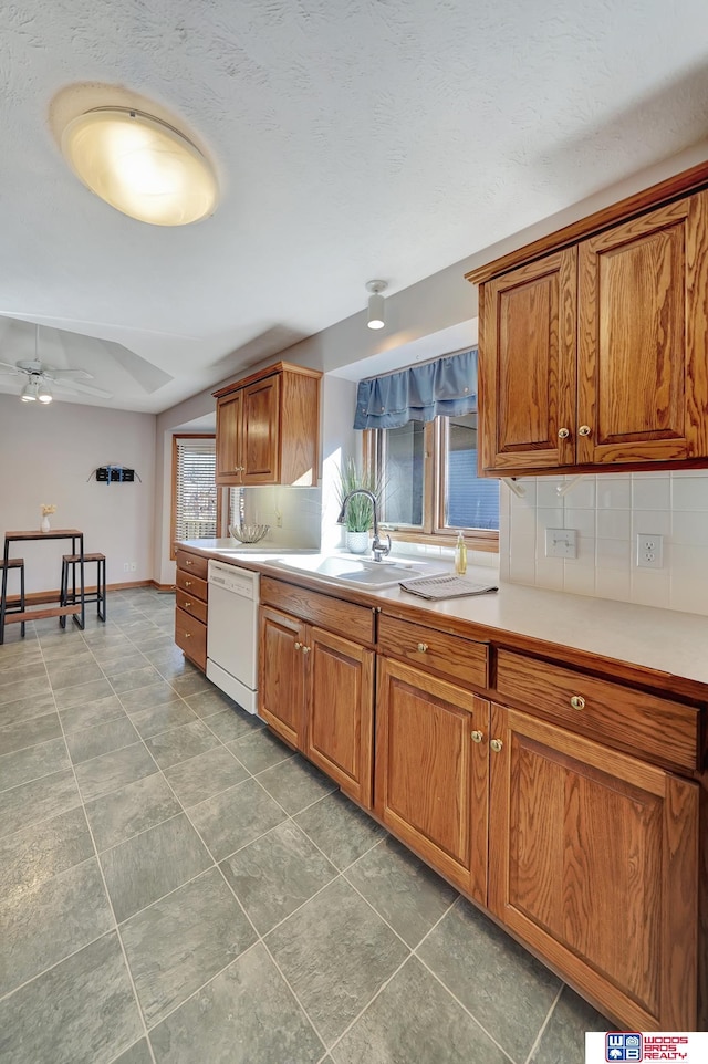 kitchen featuring white dishwasher, sink, backsplash, and ceiling fan