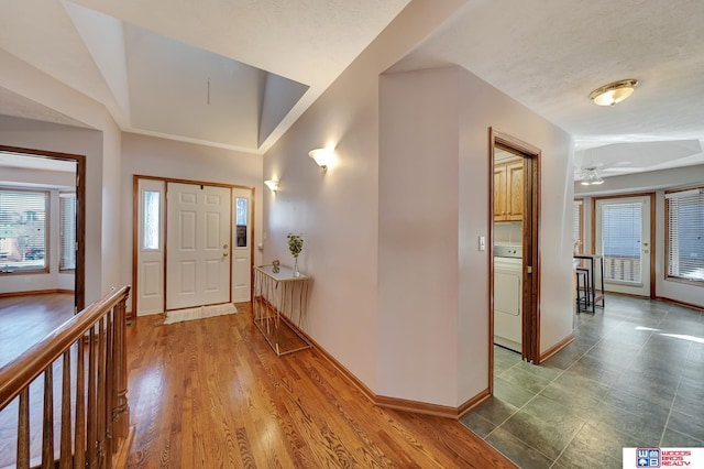 foyer entrance with washer / dryer, hardwood / wood-style floors, and a textured ceiling