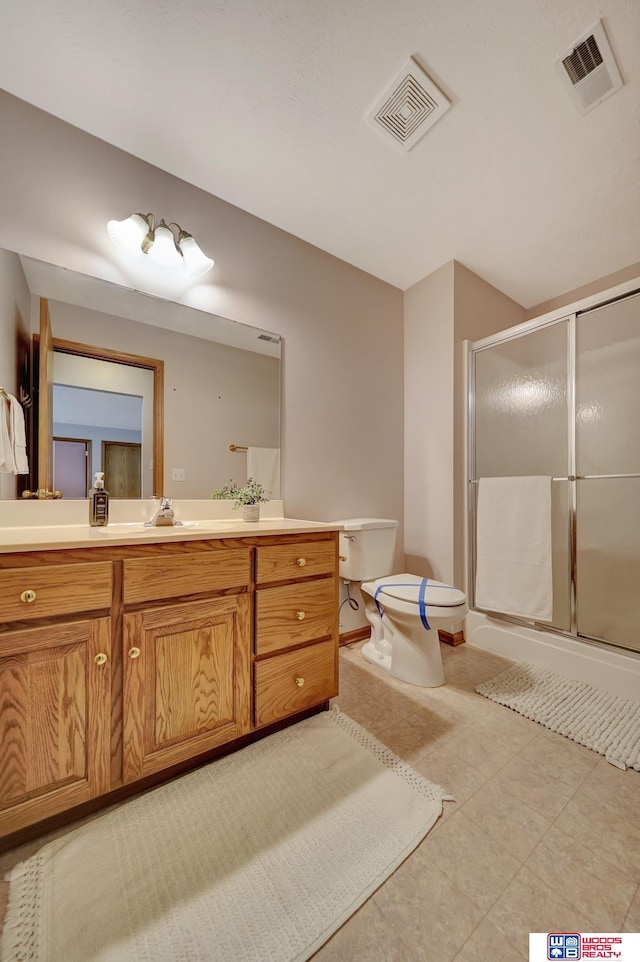 bathroom with toilet, a shower with shower door, and vanity