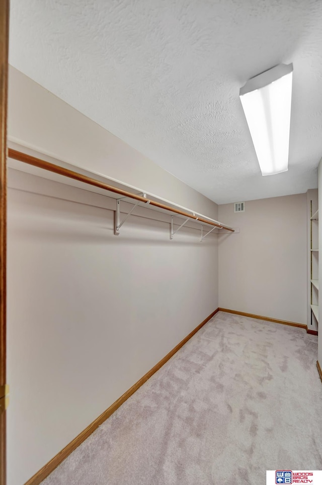 walk in closet featuring light carpet