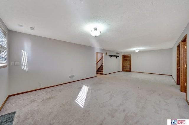 spare room with a textured ceiling and light carpet